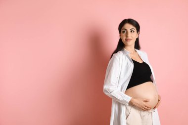 Pembe arka planda güzel hamile kadın portresi, mesaj için boşluk