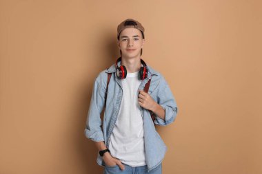 Portrait of teenage boy with backpack on dark beige background