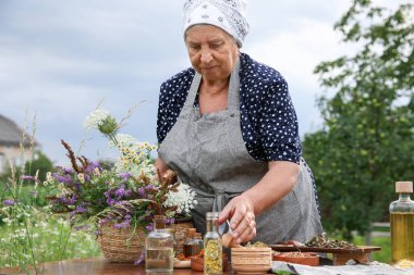 Kıdemli kadın dışarıda yemek pişiriyor.