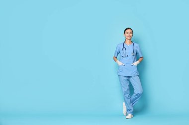 Açık mavi arka planda gülümseyen üniformalı hemşire. Metin için boşluk