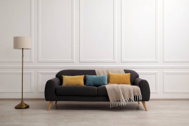 Oturma odasında yastıklı ve battaniyeli rahat gri kanepe. İç tasarım