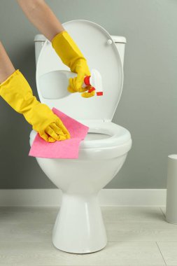 Tuvalette sprey ve paçavra temizleyen kadın, yakın plan.