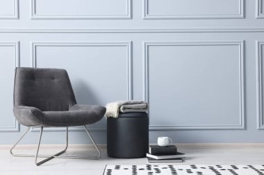 Şık tabure, sandalye ve kitaplar açık gri duvarın yanında, metin için yer var.