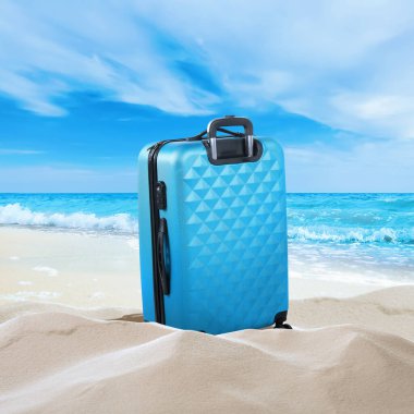 Denize yakın kumsalda açık mavi bir bavul.