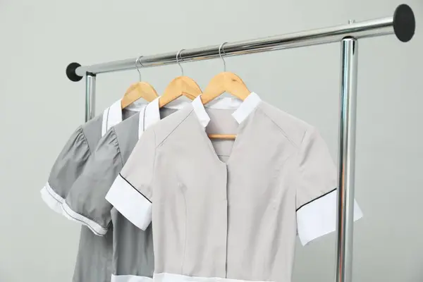 stock image Maids' uniforms on clothing rack against grey background