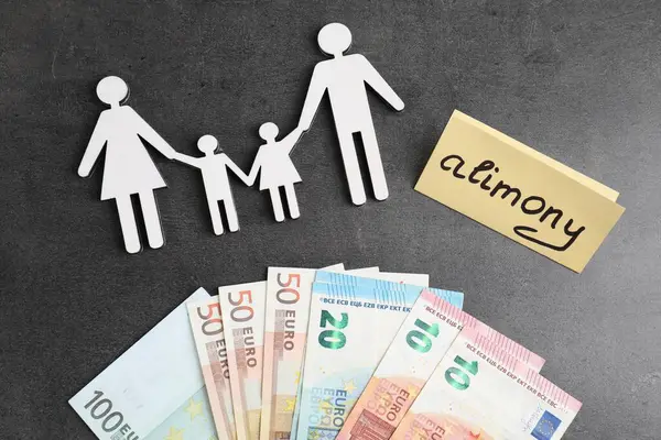 Sözcüklü bir kart, Avro banknotları ve aile figürleri gri masada, düz yatıyordu