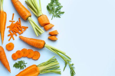 Açık arkaplanda yeşil yapraklı taze havuçlar, düz bir zemin. Metin için boşluk