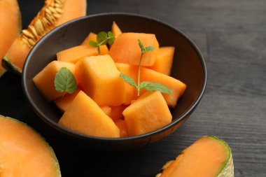 Olgun kavun parçaları koyu ahşap masada kasede, yakın plan.