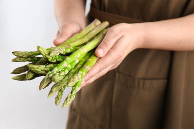 Taze kuşkonmazlı kadın açık gri arka planda, yakın planda.