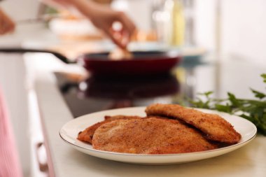 Plate of tasty schnitzels on table in kitchen, closeup clipart