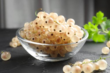 Kasede taze kuşüzümü ve gri desenli masada yeşil yapraklar, yakın plan.