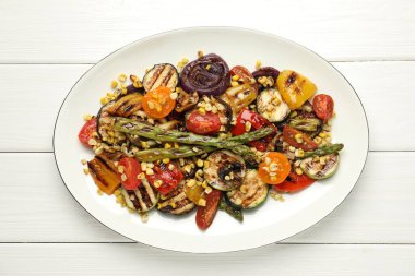 Beyaz ahşap masada ızgara sebzeli leziz salata.