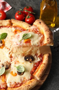 Gri masada lezzetli vejetaryen pizzasından bir parça alıyorum, yakın plan.