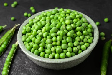 Siyah masada taze bezelyeler ve kabuklar.