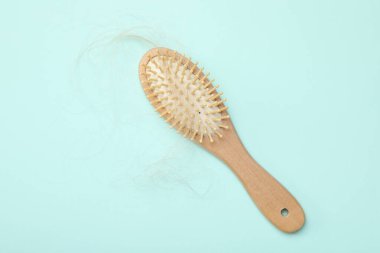 Açık mavi arka planda saçı dökülmüş bir fırça, üst manzara. Alopecia sorunu