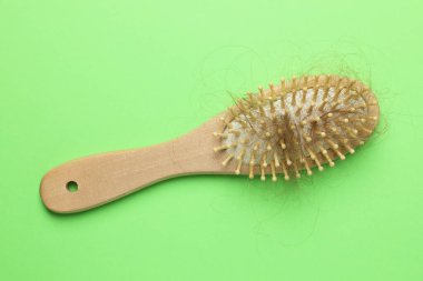 Açık yeşil arka planda saçı dökülmüş bir fırça, üst manzara. Alopecia sorunu