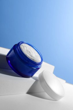 Açık mavi arkaplana karşı kavanozdaki yüz kreminin şık sunumu