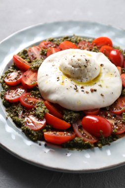 Açık gri masada taze lezzetli burrata salatası, yakın plan.