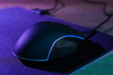 Siyah bilgisayar faresi ve fare ahşap masanın üzerinde neon ışıklarda, yakın plan
