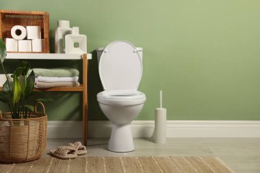 Banyoda beyaz klozet, kağıt rulo, terlik ve çiçeklerin yeri mesaj atmak için.