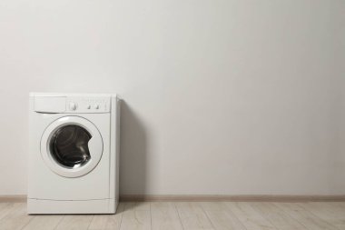 Beyaz duvarın yanında çamaşır makinesi, metin için boşluk
