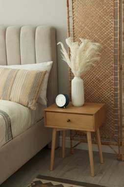 Büyük yatak, katlanır ekran ve şık bir odada komodinin yanında.