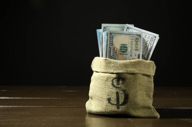 Koyu arkaplan ile ahşap masa üzerinde dolar banknotları, metin için boşluk