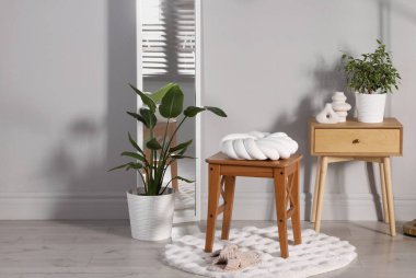 Odasında düğüm yastığı olan ahşap tabure. Şık iç tasarım