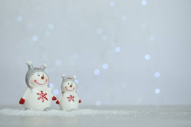 Bulanık ışıklara karşı yapay kar üzerinde tatlı dekoratif kardan adamlar. Metin için boşluk