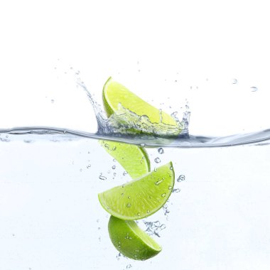 Dilimlenmiş kireç beyaz arkaplana karşı suya düşüyor