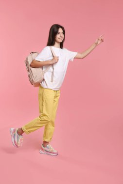 Sırt çantası ve pembe arka plan kitapları olan tatlı bir genç kız.