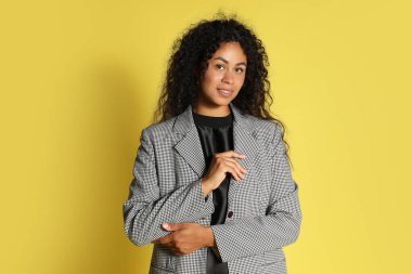 Sarı arka planda şık ceketli güzel bir kadın.