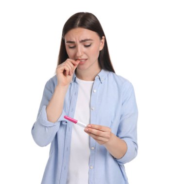 Beyaz arka planda hamilelik testi tutan kafası karışmış bir kadın.