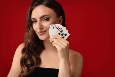 Poker oyunu. Kırmızı arka planda iskambil kartları olan çekici bir kadın. Metin için boşluk