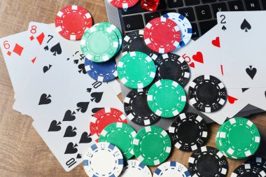 Poker fişleri, dizüstü bilgisayar, tahta masada kağıt ve zar oynamak, düz yatış. Çevrimiçi oyun