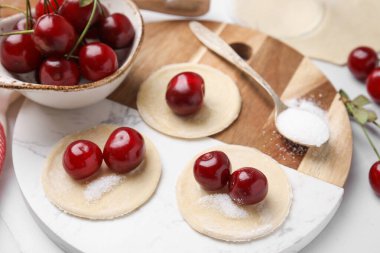 Kirazlı hamur tatlısı yapma süreci (varenyky). Çiğ hamur ve malzemeler beyaz döşeme üzerinde