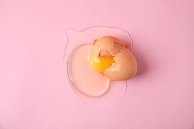 Kırık çiğ yumurta, pembe arka planda kabuk, üst manzara.