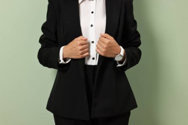 Hafif zeytin arka planda şık siyah takım elbiseli kadın, yakın plan.