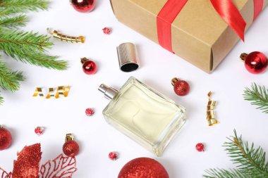 Beyaz arka planda parfüm şişesi ve Noel dekoru olan kompozisyon.