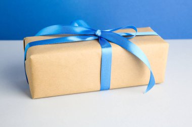 Arkaplanda mavi saten fiyonklu hediye kutusu