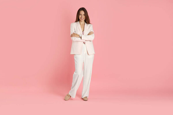 Beautiful woman in stylish white suit on pink background