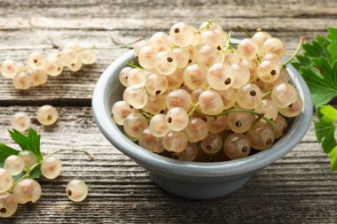 Kasede taze üzümlü üzümler ve ahşap masada yeşil yapraklar, yakın plan.