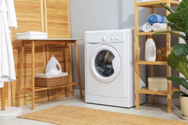 Çamaşır makinesi, havlu ve deterjanlar çamaşır odasında.