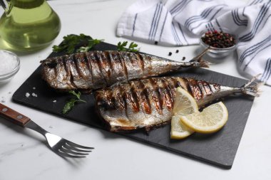 Lezzetli ızgara uskumru, maydanoz, baharat ve limon beyaz masada.