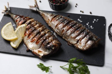 Lezzetli ızgara uskumru, maydanoz, baharat ve limon beyaz masada.