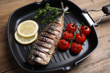 Lezzetli ızgara uskumru, domates, maydanoz ve limon ahşap masada, yakın plan.