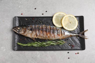 Lezzetli ızgara uskumru, biberiye, limon ve biber. Gri masa, üst manzara.