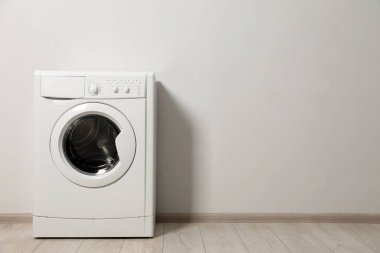 Beyaz duvarın yanında çamaşır makinesi, metin için boşluk