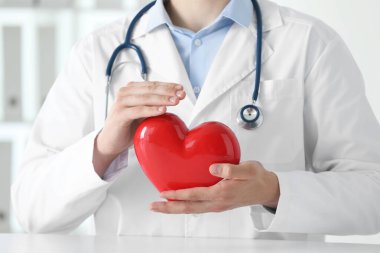 Klinikteki beyaz masada kırmızı kalpli doktor, yakın plan.