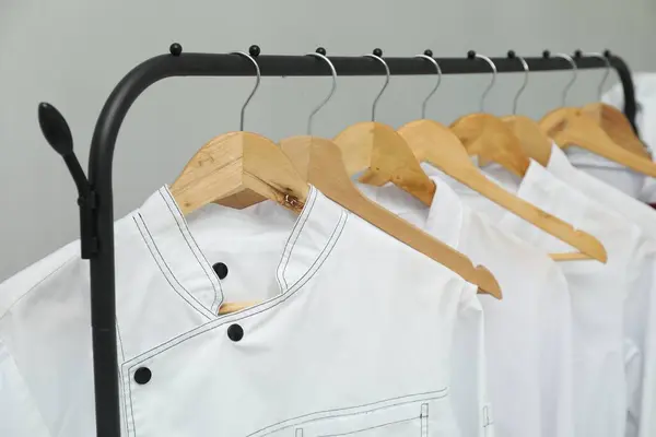 stock image Chefs' uniforms on clothing rack against grey background, closeup